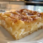A golden-brown apple cinnamon cottage cheese bake on a rustic wooden table.